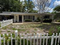 Quaint single-story home with a white picket fence and mature trees in the front yard at 2451 Loma Linda St, Sarasota, FL 34239