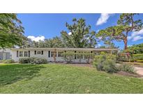 Charming single-story home featuring a well-manicured lawn and welcoming front entrance with lots of shade trees at 2462 Hyde Park St, Sarasota, FL 34239