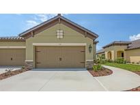 Beige two-car garage with stone accents and manicured landscaping in front of a Florida home at 248 Altamura Cir, Nokomis, FL 34275