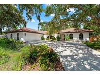 Beautiful home exterior with mature landscaping, red tile roof, and a spacious driveway at 2504 Tanglewood Dr, Sarasota, FL 34239
