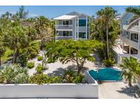 Beautiful two-story home with balconies, lush landscaping, and a unique turquoise gate at 401 N Bay Blvd, Anna Maria, FL 34216