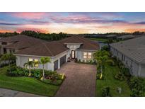 Beautiful front exterior of home with meticulously landscaped front yard and brick driveway with a view of the water at 4915 Kiva Cir, Bradenton, FL 34211