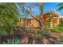 Inviting backyard featuring tropical foliage, garden beds, and a charming swing for relaxing outdoors at 6806 Palm Dr, Holmes Beach, FL 34217