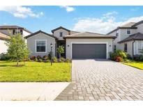 Beautiful single-story home featuring a paver driveway, a two-car garage, and lush landscaping at 15115 Oxford Grey Dr, Bradenton, FL 34211