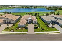 Stunning aerial view of a home with lush landscaping and a beautiful lake backdrop in a golf community at 3936 Santa Caterina Blvd, Bradenton, FL 34211