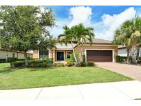 Beautiful single Gathering home featuring a tile roof, brick driveway, and lush landscaping with palm trees at 4916 Tivoli Run, Bradenton, FL 34211