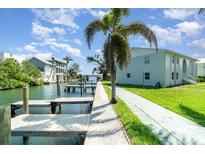Beautiful waterfront view with docks, canal and palm trees alongside the condo building on a sunny day at 522 Pine Ave # 8B, Anna Maria, FL 34216