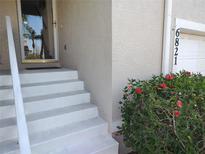 Home's entrance features stairs to the front door and colorful red flowers at the base of the house at 6821 Fairview Ter # 6821, Bradenton, FL 34203