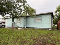 Charming single-story home with a light blue exterior, lush green lawn, and mature trees at 7555 15Th N St, St Petersburg, FL 33702