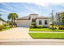 Charming single-Gathering home featuring a well-manicured lawn, and a two-car garage, under a clear blue sky at 9292 Tequila Sunrise Dr, Sarasota, FL 34241