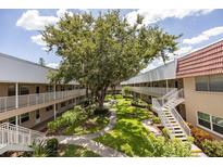 Beautiful courtyard featuring a large tree, lush landscaping, walking paths, and multiple levels of residences at 10037 62Nd N Ter # 23, St Petersburg, FL 33708