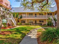 Condo exterior with lush landscaping, stairs, and walkways under a canopy of mature trees at 10037 62Nd N Ter # 23, St Petersburg, FL 33708