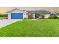 Charming single-story home with a well-manicured lawn, blue garage door, and inviting landscaping at 1071 Owl Dr, Englewood, FL 34223