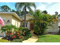 Charming home featuring a well-manicured lawn, tropical plants, and inviting walkway to the front door at 12113 Whistling Way, Lakewood Ranch, FL 34202