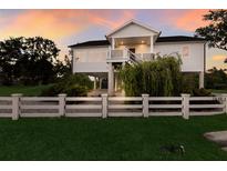 Charming two-story waterfront home featuring a white picket fence, lush landscaping, and elevated construction at 1610 Bayshore Dr, Terra Ceia, FL 34250