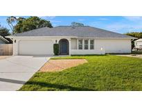 Charming single-story home featuring a well-maintained lawn and attached two-car garage at 19897 Midway Blvd, Port Charlotte, FL 33948