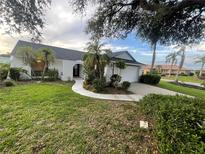 Charming single-story home with lush landscaping, palm trees, and a well-maintained lawn at 2200 E Village Ct, Venice, FL 34293