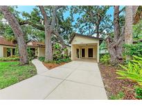 Charming home exterior featuring a concrete driveway, attached carport, and mature trees with beautiful landscaping at 2237 Circlewood Dr # 18, Sarasota, FL 34231
