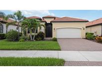 Charming home featuring a barrel tile roof, manicured lawn, and a two-car garage at 25143 Spartina Dr, Venice, FL 34293