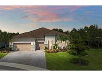 Charming single-story home featuring a tile roof, paver driveway, three-car garage, and meticulously landscaped front yard at 3379 Chestertown Loop, Bradenton, FL 34211