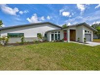 A modern home featuring a well-manicured lawn, contemporary architectural design, and a striking red door at 3636 Mineola, Sarasota, FL 34239