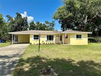 Charming yellow home with a well-manicured lawn, carport, and classic shutters at 5350 Barbarossa Ave, Sarasota, FL 34235