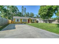 Charming single-story home featuring a well-maintained lawn, a long driveway and a bright red front door at 5438 Potter St, Sarasota, FL 34232