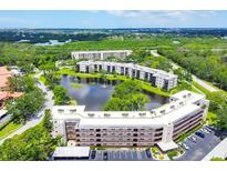 An aerial view of a condo community featuring a central lake, mature trees, and well-maintained buildings at 6188 80Th N St # 102, St Petersburg, FL 33709