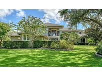 Stately home featuring manicured lawn, lush landscaping, and a grand entrance with large windows and decorative trees at 6905 Pine Valley St, Bradenton, FL 34202