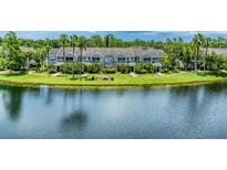 Waterfront condo buildings with lush landscaping and palm trees offer serene living at 8827 Manor Loop # 208, Lakewood Ranch, FL 34202