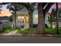 Charming blue two-story home with a bright yellow front door and inviting front porch and mature trees at 112 17Th E St, Bradenton, FL 34208