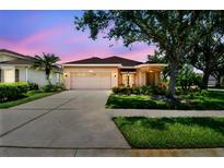 Charming single-story home featuring a two-car garage, manicured lawn, and colorful landscaping at 1415 Millbrook Cir, Bradenton, FL 34212