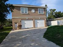 Two-story home with a double garage and a light brown facade in need of renovation at 3006 Hawthorne St, Sarasota, FL 34239