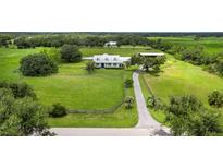 Expansive aerial view of a beautiful white home on lush green property with pond, barn, and surrounding mature trees at 3100 Lena Ln, Sarasota, FL 34240