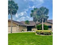 Charming single-story home with a lush lawn, stone accents, and beautiful palm trees at 3764 Torrey Pines Blvd, Sarasota, FL 34238