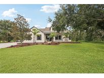 Charming two-story home featuring a lush green lawn and mature trees against a clear blue sky at 3906 Twin Rivers Trl, Parrish, FL 34219