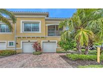 Inviting two-story townhome featuring attached garages, red brick driveway, and lush tropical landscaping at 4267 Expedition Way, Osprey, FL 34229