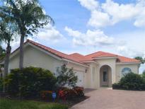 Charming single-story home with a red tile roof, brick driveway, arched entryway, and well-maintained landscaping at 5779 Wilena Pl, Sarasota, FL 34238