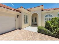 Inviting front entrance with arched doorway and red brick driveway leading to attached garage at 5779 Wilena Pl, Sarasota, FL 34238