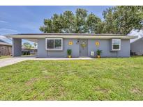 Charming single-story home with gray siding, sunflowers, a well-manicured lawn and a convenient carport at 8258 San Jacinto Ave, North Port, FL 34287