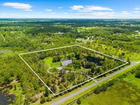Stunning aerial view of property, highlighting lush landscaping, a private pond, and a winding driveway at 21705 67Th E Ave, Bradenton, FL 34211