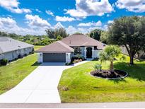 Beautiful single-story home with a well-manicured lawn, lush landscaping, and a freshly sealed driveway at 234 Antofagasta St, Punta Gorda, FL 33983