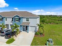 Two-story townhome boasts manicured landscaping, a one car garage, and a driveway with multiple parked cars at 2824 Pearly Banks Dr, Bradenton, FL 34208