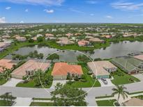 Aerial view of a single-Gathering home with red tile roof, a lake view, and lush landscaping in a gated community at 2937 Seasons Blvd, Sarasota, FL 34240