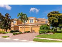 Charming two-story townhome with tile roof, attached garages, manicured landscaping, and a brick driveway at 318 Winding Brook Ln # 104, Bradenton, FL 34212