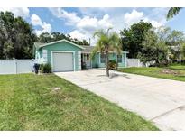 Charming single-story home with a well-maintained lawn, fenced yard, and a paved driveway leading to an attached garage at 327 Francis Dr, Apollo Beach, FL 33572