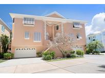 Charming two-story peach home with two-car garage and well-maintained landscaping under a clear blue sky at 3954 Hamilton Club Cir # 14, Sarasota, FL 34242