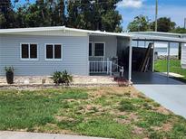 Charming single-story home featuring light-grey siding, a covered carport, and a cozy front porch at 5316 Chateau Ln, Bradenton, FL 34207