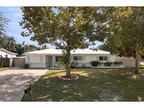 Charming one-story home featuring a well-manicured lawn, mature trees and light blue accents at 6180 42Nd N Ave, St Petersburg, FL 33709