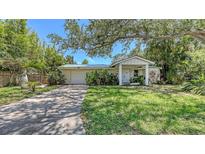 Inviting single-story home with a lush front yard, mature trees, and a cozy, covered front porch at 626 46Th St, Sarasota, FL 34234